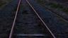 Railway tracks with rust-colored rails and gravel ballast at dusk. Photo: W.carter via Wikimedia Commons, CC0 1.0 (cropped)