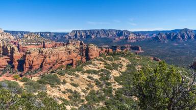 Red rock cliffs and a juniper-covered ridge under a clear blue sky. Photo: Coconino National Forest via Wikimedia Commons, CC0 1.0 (cropped)