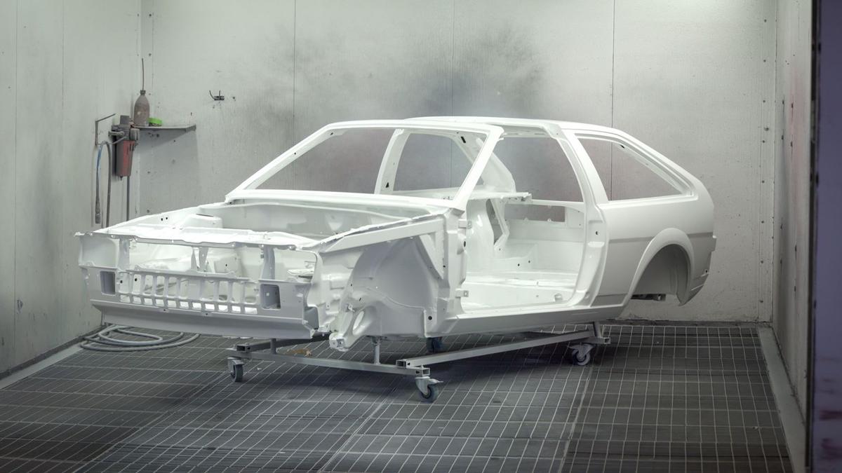 A vintage car frame painted white inside an industrial paint booth. Photo: Vladan Rajkovic on Pexels