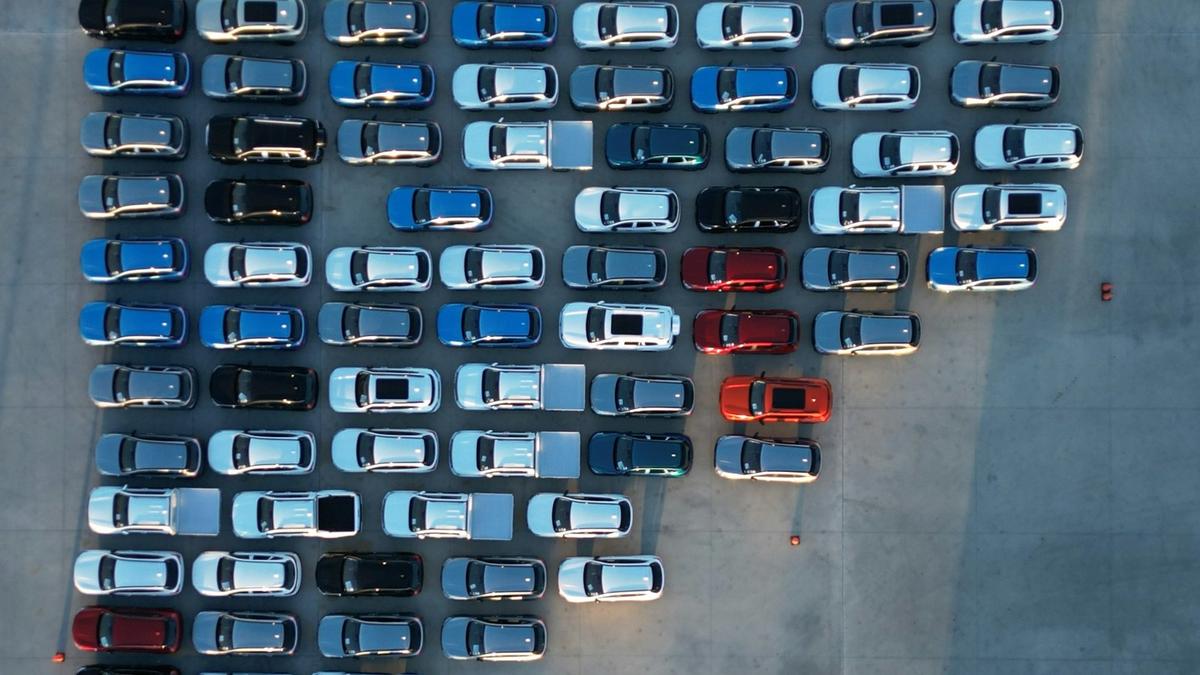 Aerial view of rows of parked cars on a concrete lot at dusk. Photo: Iain Kennedy (@photoken123) on Unsplash