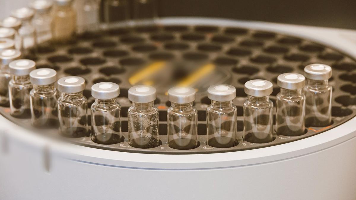 Glass vials in a laboratory carousel with brand marks blurred. Photo by Jess Loiterton on Pexels.