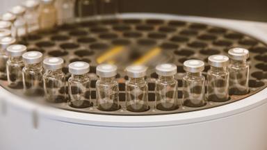 Glass vials in a laboratory carousel with brand marks blurred. Photo by Jess Loiterton on Pexels.