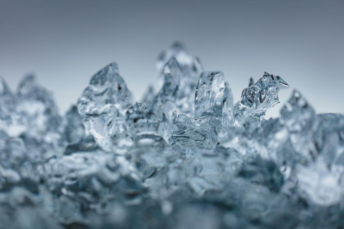 Close-up of melting ice crystals against a gray background. Photo: Khamkéo on Unsplash