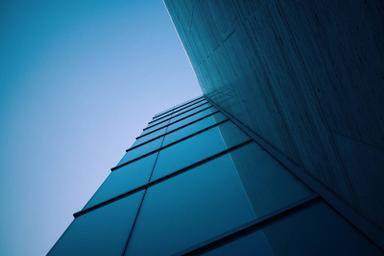 Corner of a glass office building seen from below against a blue sky. Photo: Jonathan Simcoe / Wikimedia Commons, CC0