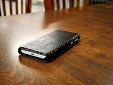 Black leather-cased smartphone lying on a wooden table. Photo: Santeri Viinamäki / Wikimedia Commons, CC BY-SA 4.0